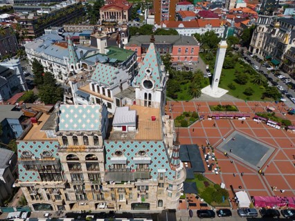 Detailed architecture with central square and green park, mountains in the background, aerial view,