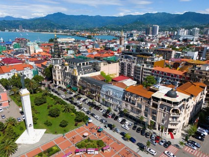 Historic buildings and central squares in a colourful coastal town with mountains, aerial view,