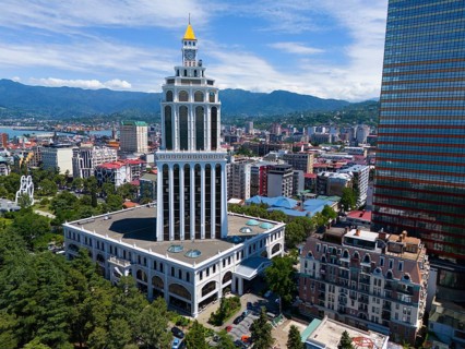 Tall building in a city with mountain backdrop and blue sky, aerial view, Sheraton Hotel, Batumi,