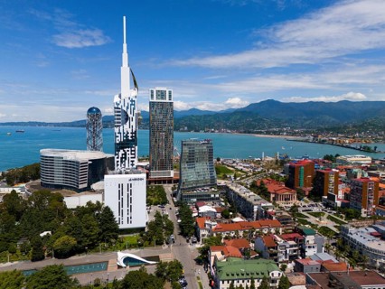 Modern high-rise buildings on the seashore with mountain panorama and clear sky, aerial view,