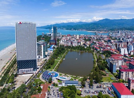 High-rise buildings on the beach with park, lake and mountains in the background, aerial view,