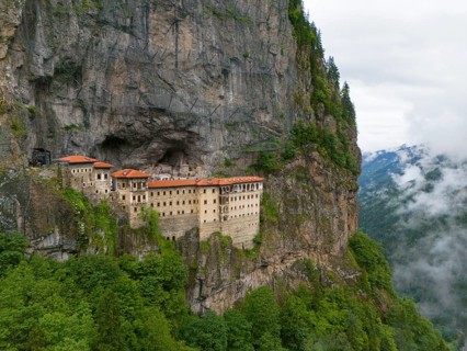 A mystical monastery in a misty rocky landscape, high above the green surroundings, aerial view,