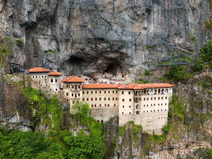Monastery built into the rock with red roofs, surrounded by steep rock faces, aerial view, Sumela