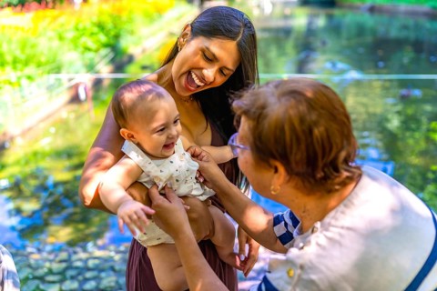 Happy latin family enjoying a sunny day in a park, mother holding her baby while grandmother is