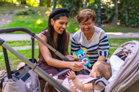 Grandmother, mother and baby girl enjoying time together at the park, mother feeding her baby solid