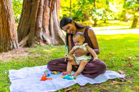 Latin mother and her baby daughter enjoying playtime with colorful toys on a blanket, creating a