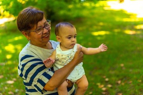 Smiling grandmother cradling her adorable granddaughter in a vibrant green park, enjoying a sunny