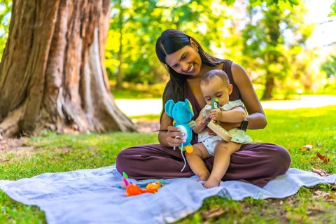 Latin mother and her baby daughter enjoying playtime with colorful toys while sitting on a blanket