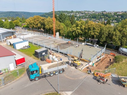 Aerial view of a construction site with large vehicles and active construction work, car park