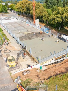 Workers and machines concreting on a construction site under a large crane, car park construction,