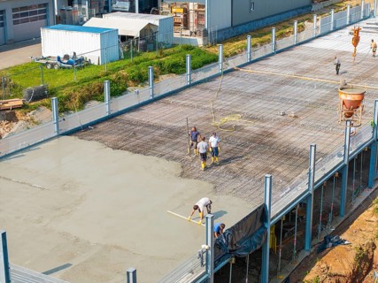 Construction workers working on a concrete surface on a building site in a green environment, car