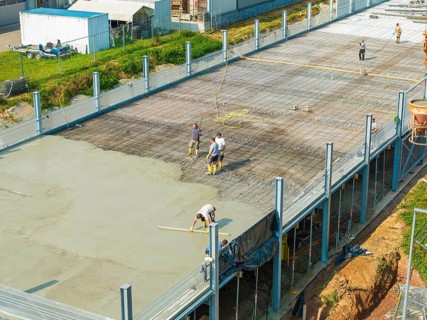 Workers on a construction site smoothing concrete surfaces and using tools, car park construction,