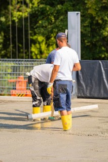 Close-up of construction workers concreting on a building site with safety equipment, car park