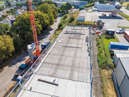 Crane over a construction site with workers and surrounding streetscape and landscape, car park