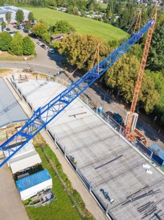 View from above of a construction site with a blue crane and construction workers, surrounded by