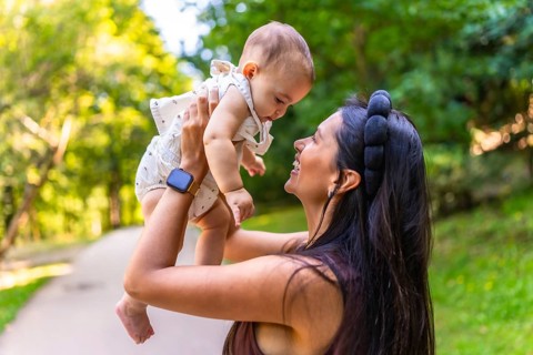 Happy latin mother lifting her baby high in the air, enjoying playful moments and laughter in a
