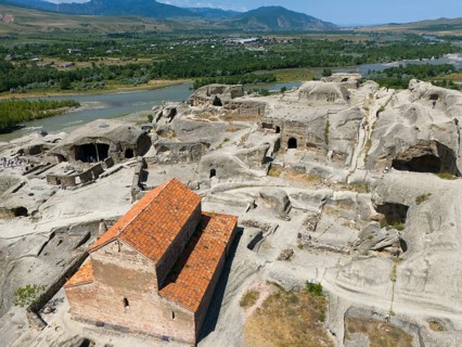Older sandstone church in a rocky and green valley landscape by the river, aerial view, Princes'