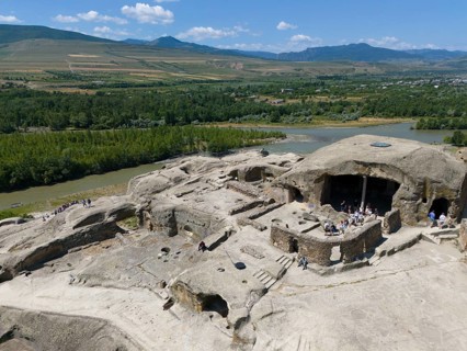 Ancient ruins with tourist visitors, surrounded by river landscapes and mountains, aerial view,