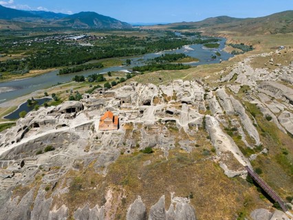 Panoramic view of a rocky landscape with embedded church and river view, aerial view, cave town