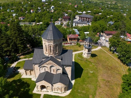 Aerial view of a church with surrounding buildings and green vegetation in a village, aerial view,