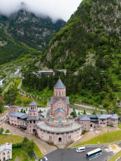 Majestic red brick church in a picturesque mountain landscape under cloudy atmosphere, aerial view,