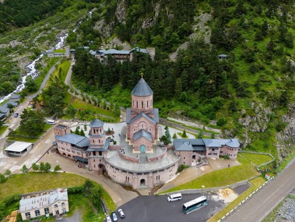 Red brick church in a picturesque mountain landscape, surrounded by forests and clouds in the sky,