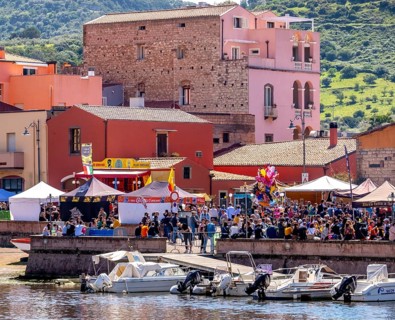 Sardinia, boats in the river Temo and residential buildings on the promenade, guests at the