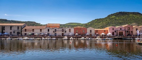Sardinia, boats in the river Temo and houses on the promenade, guests at the restaurants with