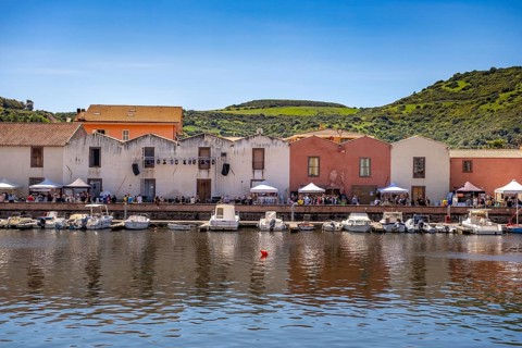 Sardinia, boats in the river Temo and residential buildings on the promenade, guests at the