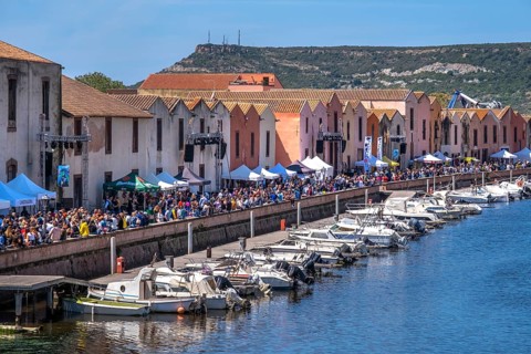 Sardinia, boats in the river Temo and houses on the promenade, guests at the restaurants with