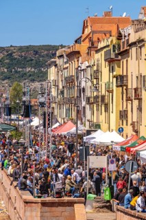 Sardinia, boats in the river Temo and houses on the promenade, guests at the restaurants with