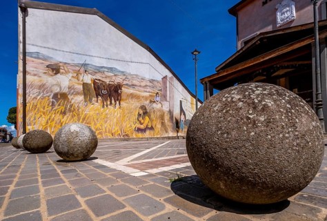 Sardinia, stone balls in front of a house with mural (Murales) Sardinia sight, Tinnura, Europe,