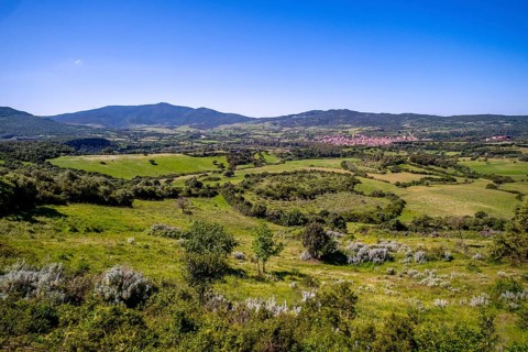 Sardinia, view of village and wide landscape meadows and fields, with mountains in the background,