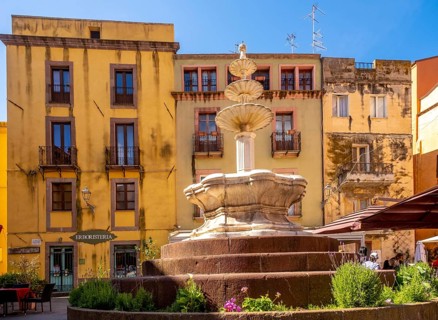 Sardinia, artistic fountain with three levels on the Piazza Costituzione, house wall with