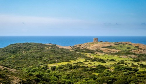 Sardinia, Former fortress tower, hilly coastal landscape by the sea, blue sky with clouds, Bosa,