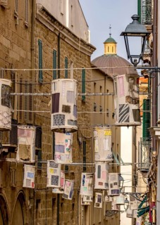 Sardinia, lanterns made of fabric remnants patchwork on power lines between the houses above the