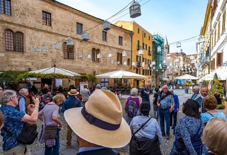 Sardinia, tourist tour group in the old town with sandstone-coloured palazzi, birdcage from house
