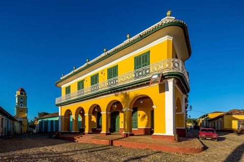 Centre of Trinidad Palacio Brunet, yellow palace with blue sky and the church Convento de San