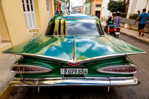 Vintage car, historic road cruiser, green Impala, streetlife in the city centre of Santa Clara at