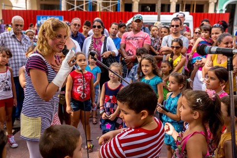 A young girl with a microphone plays clown and entertains children, Streetlife in the city centre
