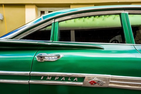 Vintage car, historic road cruiser, green Impala, streetlife in the city centre of Santa Clara at