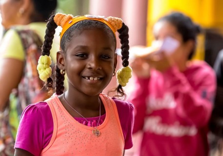 Young girl with pinned-up pigtails at a Cuban pizza stand with her family, Viñales, Cuba, Pinar del