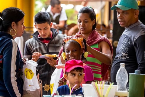 Young girl with pinned-up pigtails at a Cuban pizza stand with her family, Viñales, Cuba, Pinar del