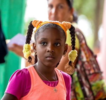 Young girl with pinned-up pigtails at a Cuban pizza stand with her family, Viñales, Cuba, Pinar del