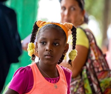 Young girl with pinned-up pigtails at a Cuban pizza stand with her family, Viñales, Cuba, Pinar del