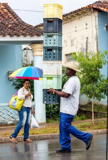 Cuban man with hat carrying and balancing crates of drinks across a street in Vinales, Viñales,