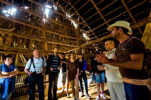Tobacco farmer Luis Manne Alvares Rodrigues explains tobacco growing to a group of tourists, drying