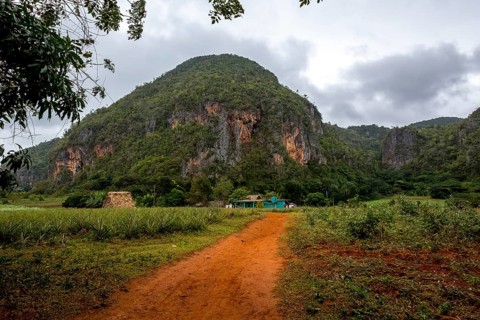 Red earth, finca, farmhouse below the overgrown hills in the Vinales Valley, Viñales, Cuba, Pinar
