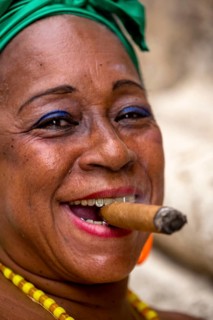 Old Cuban woman with green hair bow smokes a Havana cigar, Cuban woman with cigar and lacquered