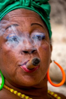 Old Cuban woman with green hair bow smokes a Havana cigar, Cuban woman with cigar and lacquered